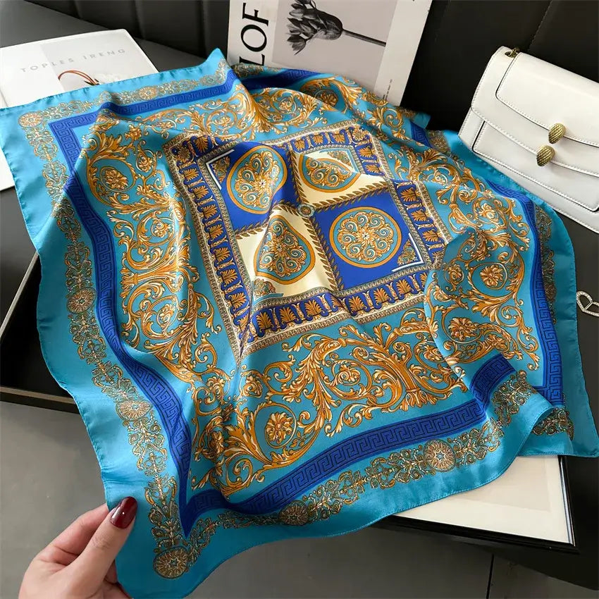 Elegant silk scarf "Bandana Miami" in blue and gold with intricate patterns, 70x70 cm, displayed on a stylish background.